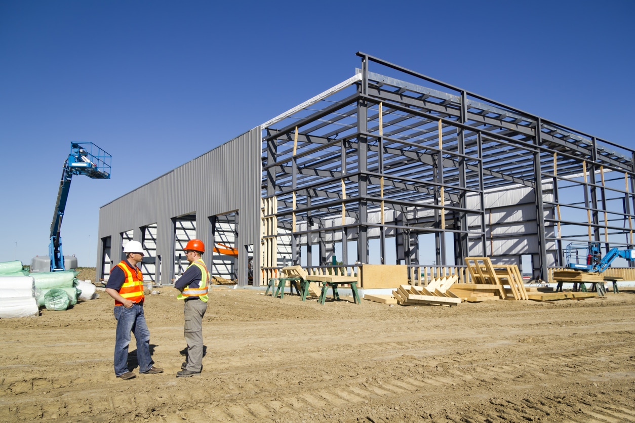 Pre-engineered metal building under construction with steel framing and workers on site